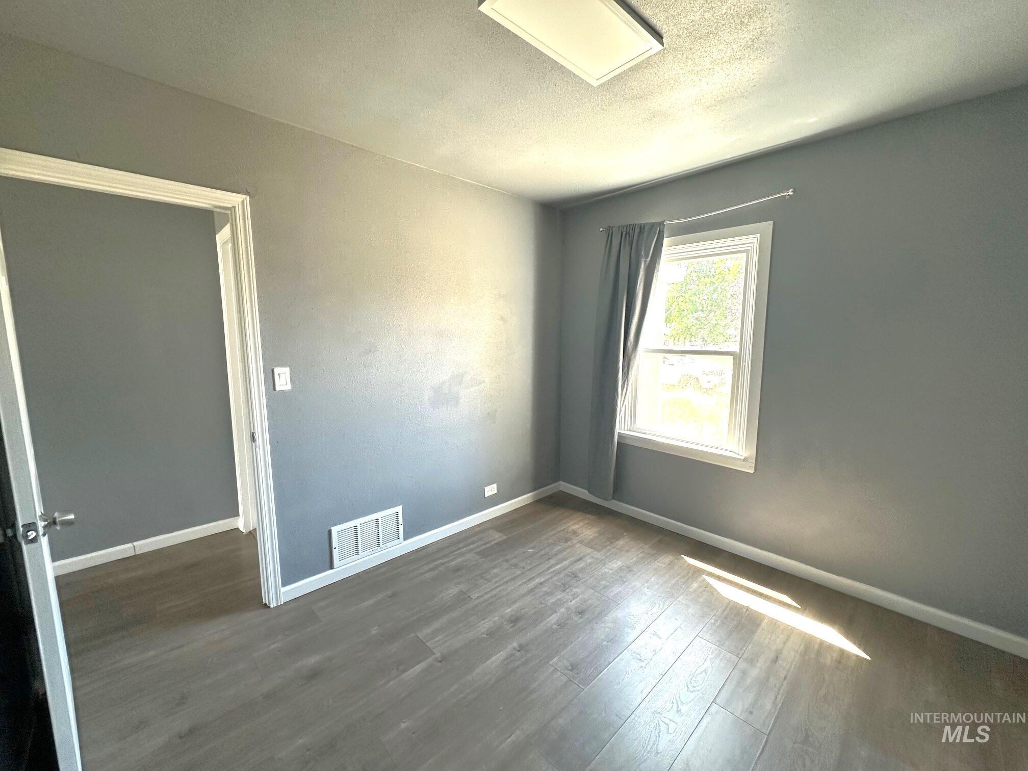 787 Southwest 3rd Street Ontario, OR 97914 - Photo 10 of 22 Empty room with dark wood finished floors and a textured ceiling