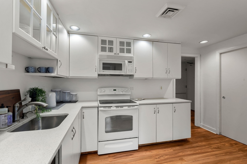 75 Grove Street, Unit 227 Wellesley, MA 02482 - Photo 13 of 29 a kitchen with stainless steel appliances granite countertop a sink a stove a microwave a refrigerator a counter space and cabinets