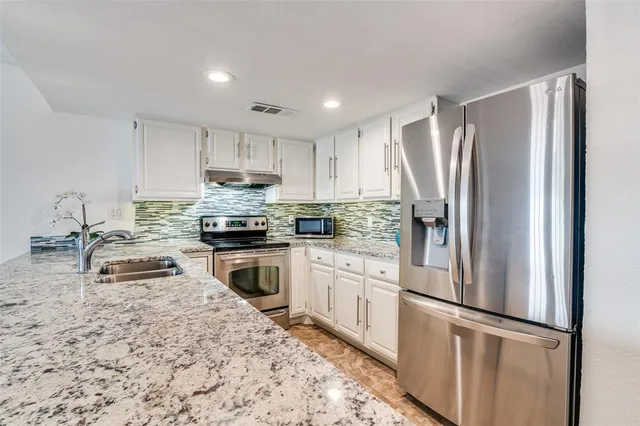 a kitchen with granite countertop a refrigerator stove and sink