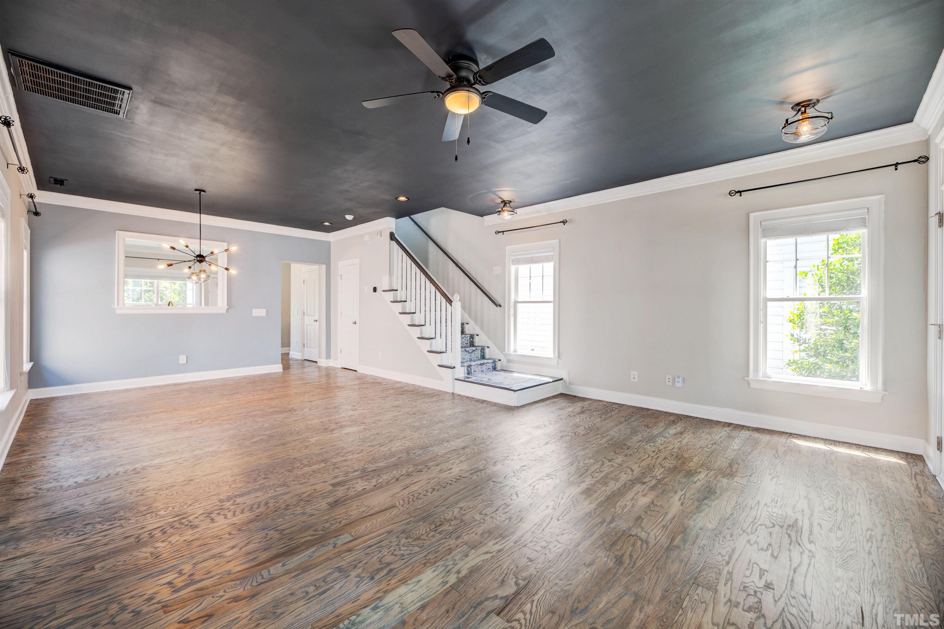 7736 ACC Boulevard Raleigh, NC 27617 - Photo 6 of 37 an empty room with wooden floor chandelier fan and windows