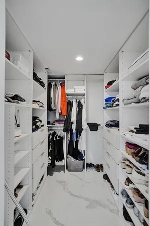 a view of walk in closet with clothes and shoes