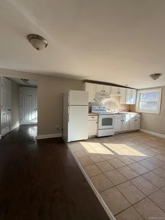 an empty room with staircase and view of kitchen