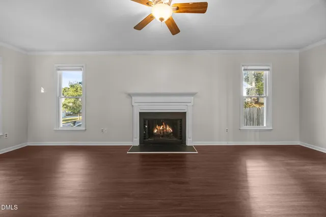 a view of an empty room with wooden floor fireplace and a window
