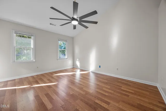 a view of empty room with wooden floor and fan