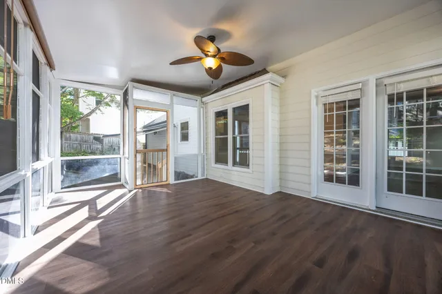 a view of an empty room with wooden floor and a large window