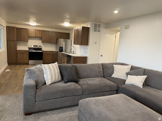 895 East Arrowhead Lane Murray, UT 84107 - Photo 3 of 12 Open-concept kitchen featuring wood-finish cabinetry, stainless steel appliances, a subway tile backsplash, and light countertops