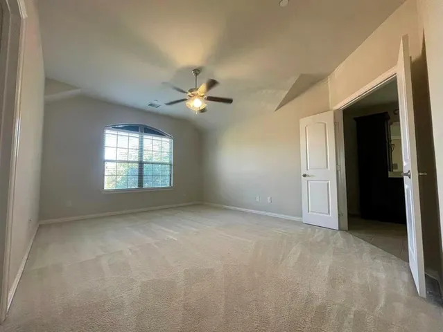 an empty room with a bathroom and a ceiling fan