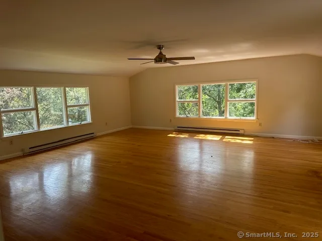 a view of empty room with wooden floor and fan