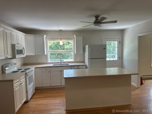 a large kitchen with stainless steel appliances granite countertop a stove a sink and a granite counter tops with white cabinets