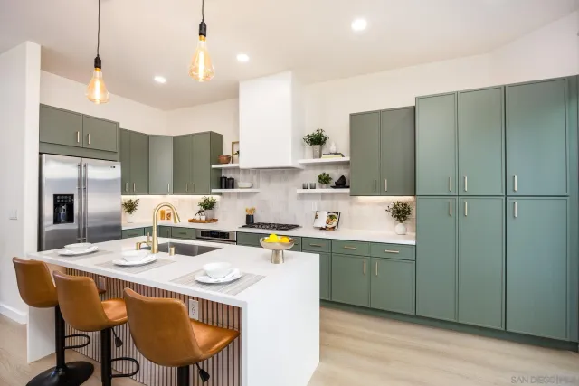 a kitchen with a sink a stove a refrigerator and white cabinets with wooden floor