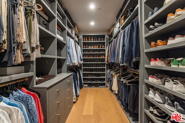 a view of walk in closet with clothes and shoes