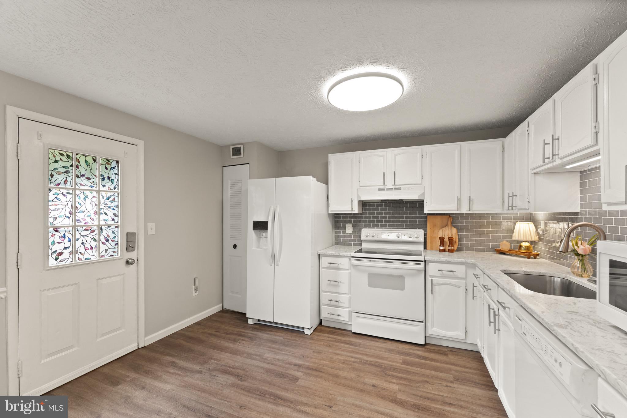 1617 Sierra Woods Drive Reston, VA 20194 - Photo 16 of 39 a kitchen with stainless steel appliances granite countertop a stove a sink and a refrigerator with wooden floors