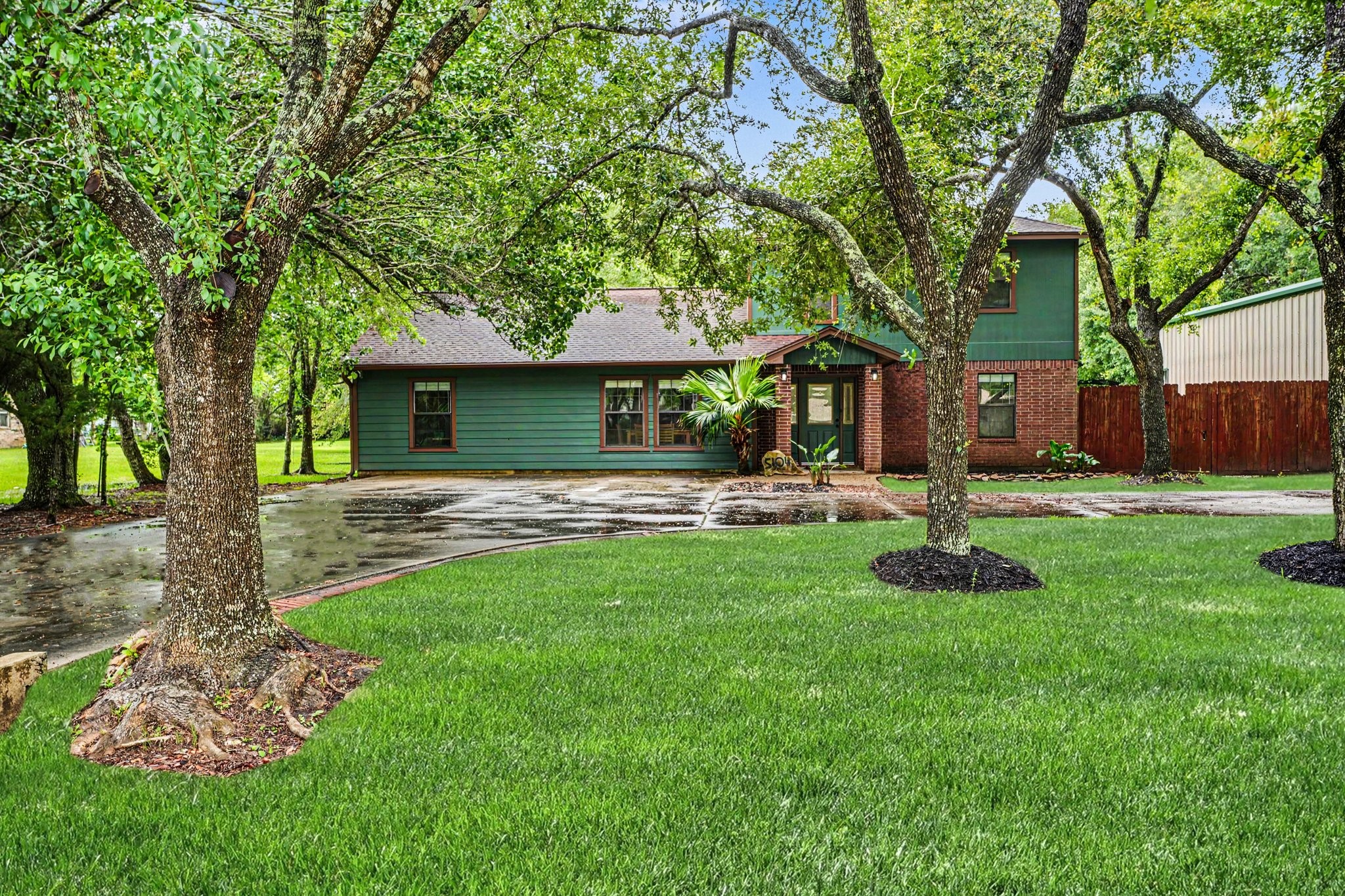 5104 Avenue R Santa Fe, TX 77510 - Photo 1 of 35 Charming home with a mix of green siding and brick exterior, featuring a well-maintained lawn and mature trees. The property offers ample driveway space and a welcoming front entrance.