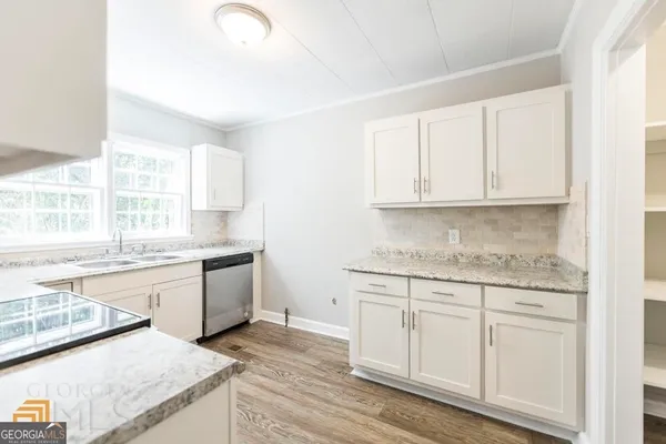 a kitchen with granite countertop white cabinets and white appliances