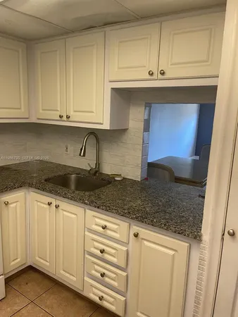 a kitchen with granite countertop white cabinets and sink