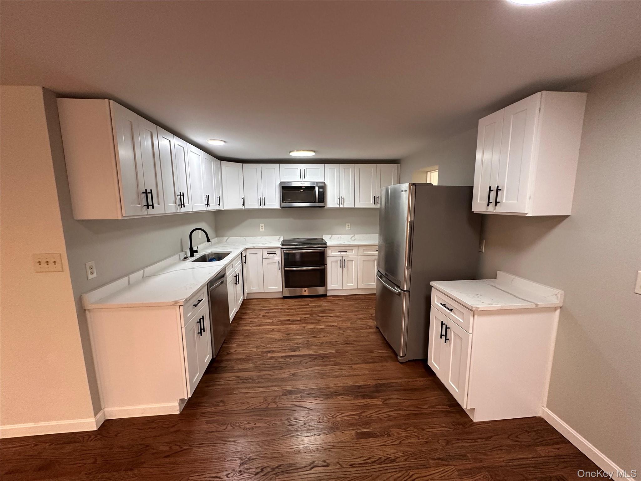 525 Plattekill Ardonia Road Wallkill, NY 12589 - Photo 9 of 25 a large kitchen with a stove top oven a refrigerator a sink and dishwasher with wooden floor