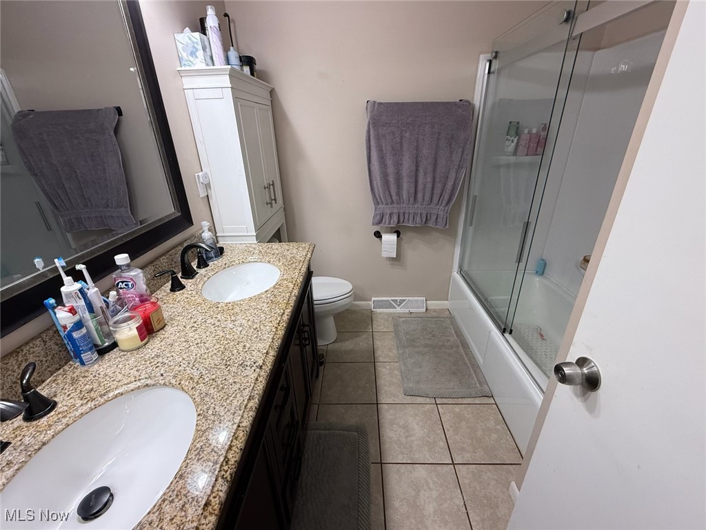 10719 Johnnycake Ridge Road Painesville, OH 44077 - Photo 14 of 21 Bathroom with double vanity, light tile patterned floors, and combined bath / shower with glass door