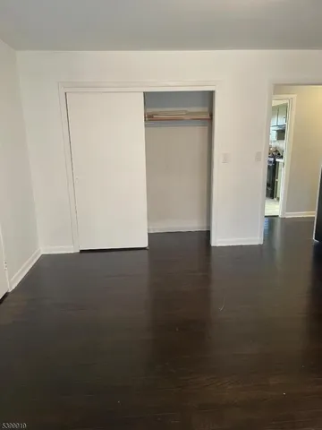a view of an empty room with wooden floor and closet