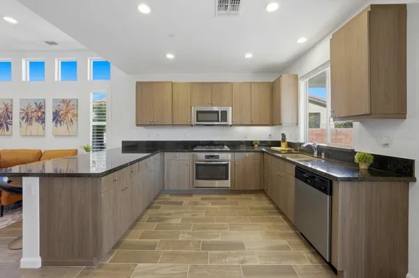 a kitchen with stainless steel appliances granite countertop a stove a sink and a refrigerator