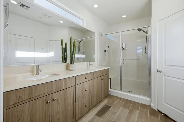a bathroom with double vanity sink and shower