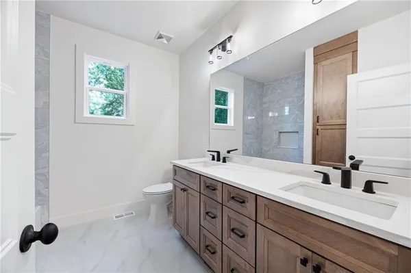 a bathroom with a double vanity sink a mirror and a toilet