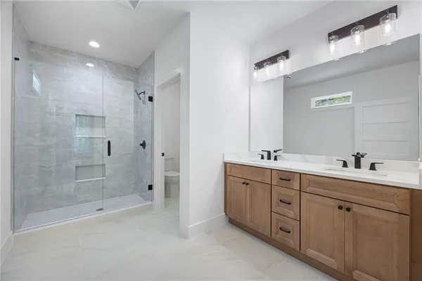 a bathroom with a double vanity sink mirror and shower