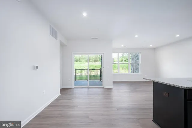an empty room with wooden floor and entrance to ceiling window