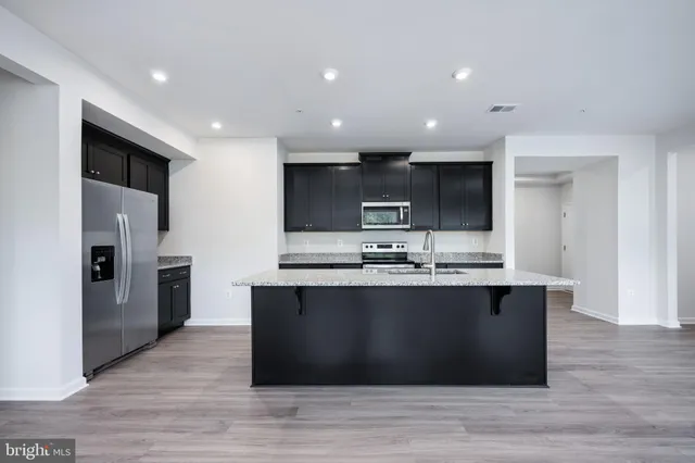 a large kitchen with stainless steel appliances granite countertop a large counter top a sink and a dishwasher