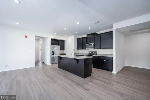 a large white kitchen with kitchen island a sink wooden floor and a refrigerator