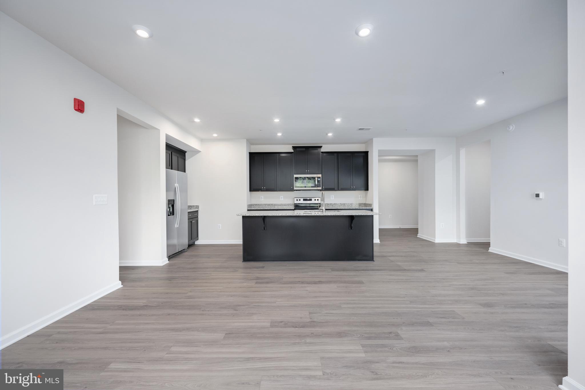 29 Hyssop Way, Unit 101 Stafford, VA 22554 - Photo 16 of 34 a large white kitchen with kitchen island a sink wooden floor and a refrigerator