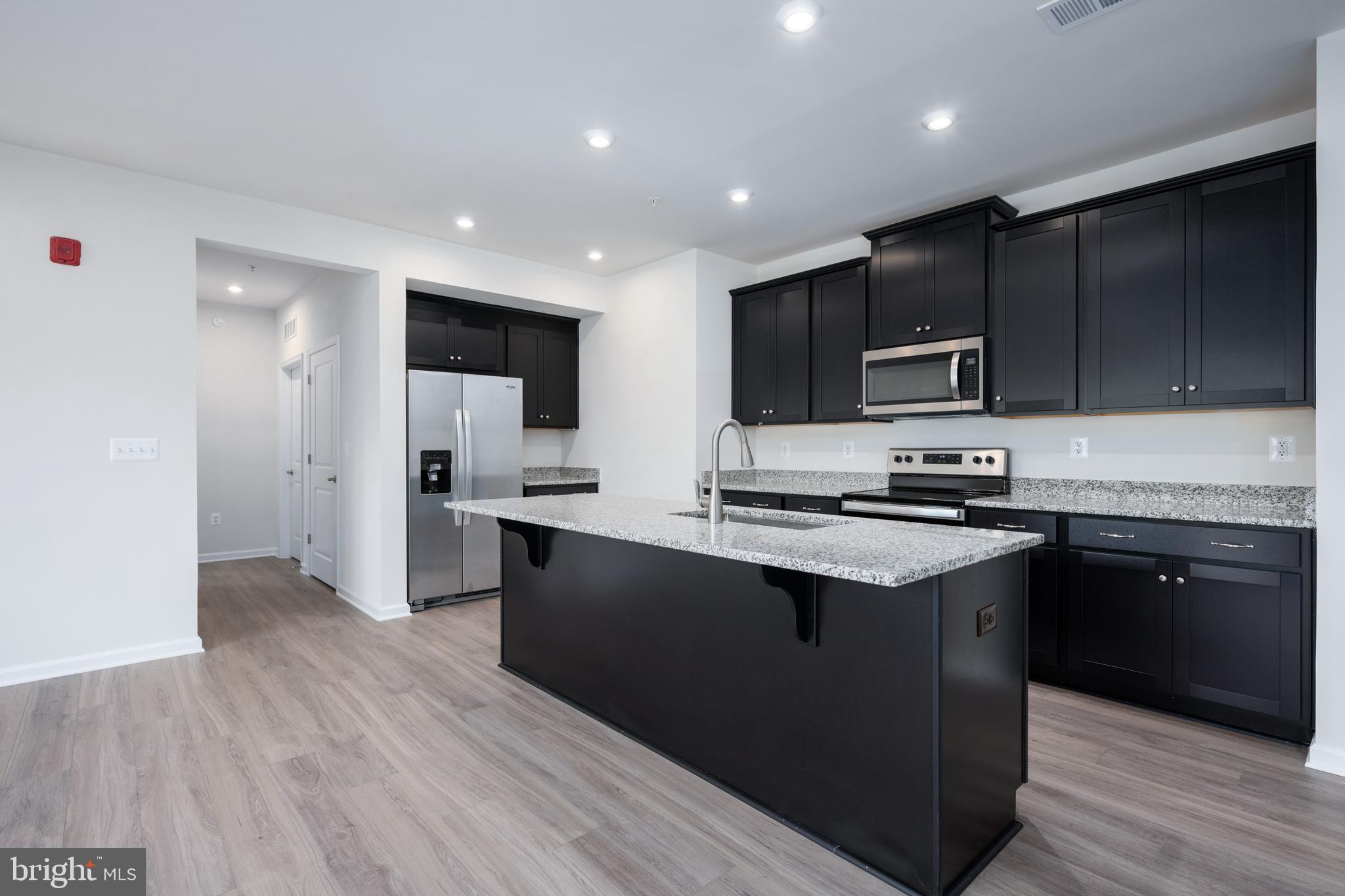 29 Hyssop Way, Unit 101 Stafford, VA 22554 - Photo 17 of 34 a kitchen with stainless steel appliances kitchen island granite countertop a stove a sink and a refrigerator