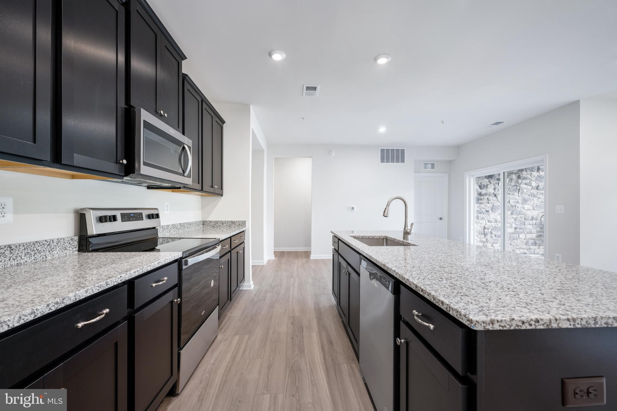 29 Hyssop Way, Unit 101 Stafford, VA 22554 - Photo 20 of 34 a kitchen with stainless steel appliances granite countertop a sink a stove top oven and wooden floor