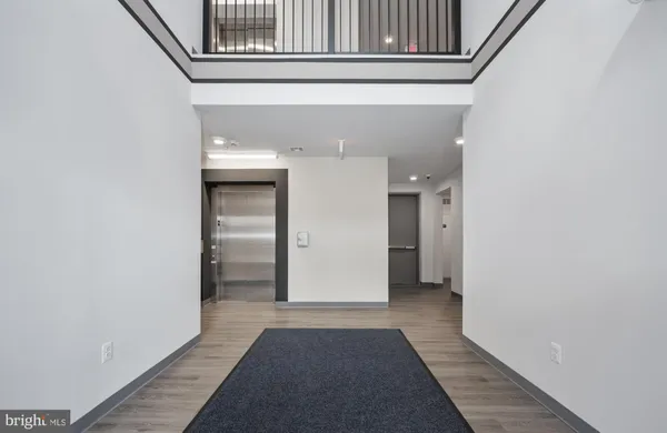 a view of a hallway with wooden floor and a bathroom
