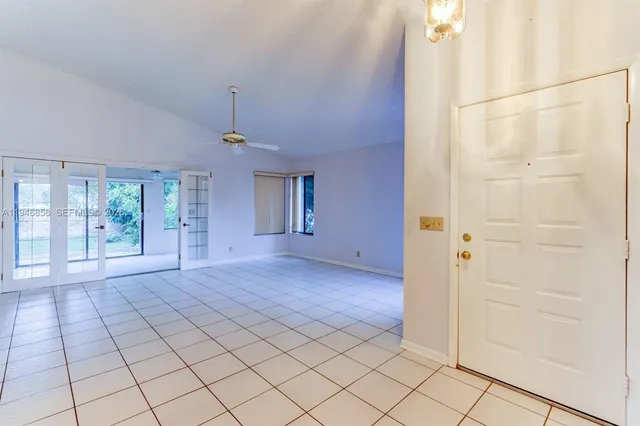 an empty room with windows and chandelier fan