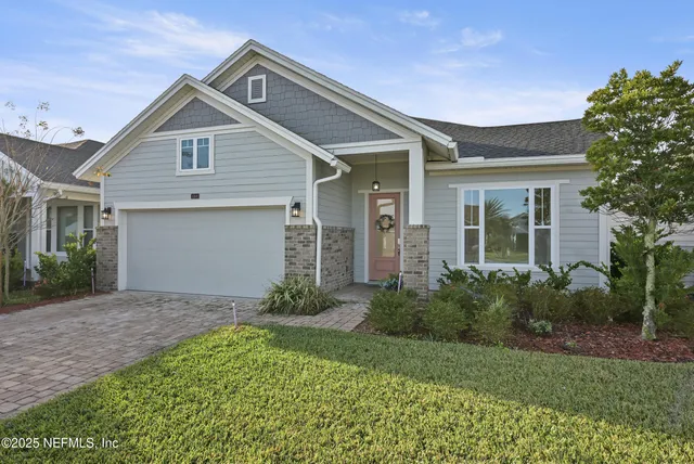 a view of a house with brick walls and a yard with plants