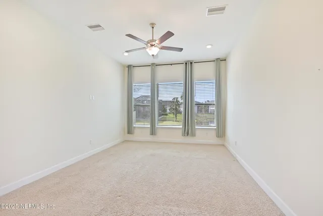 a view of a room with a ceiling fan and entryway