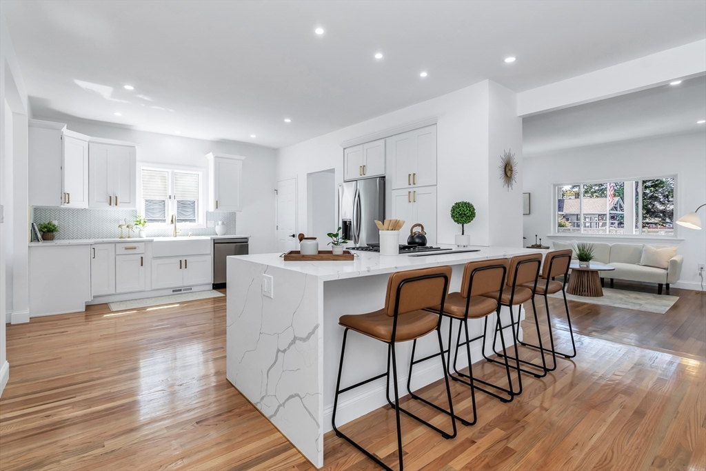 a kitchen with stainless steel appliances kitchen island granite countertop a table chairs sink and cabinets