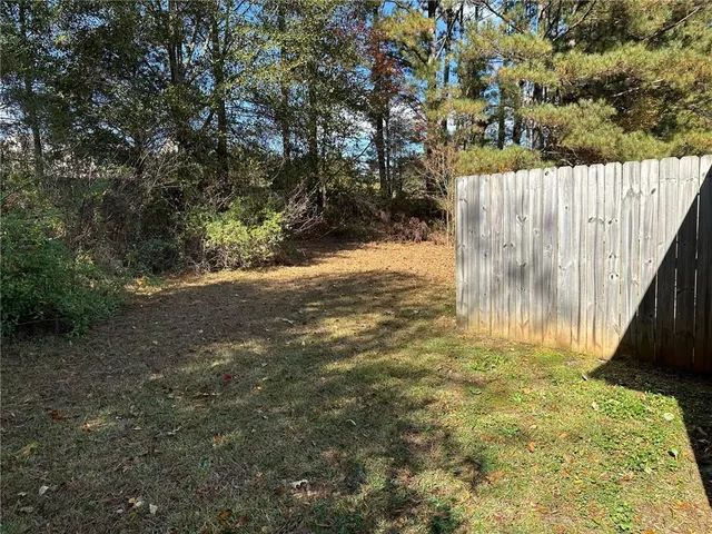 a view of backyard with wooden fence and a large tree