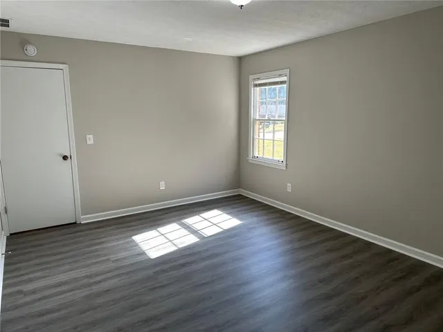 an empty room with wooden floor and windows