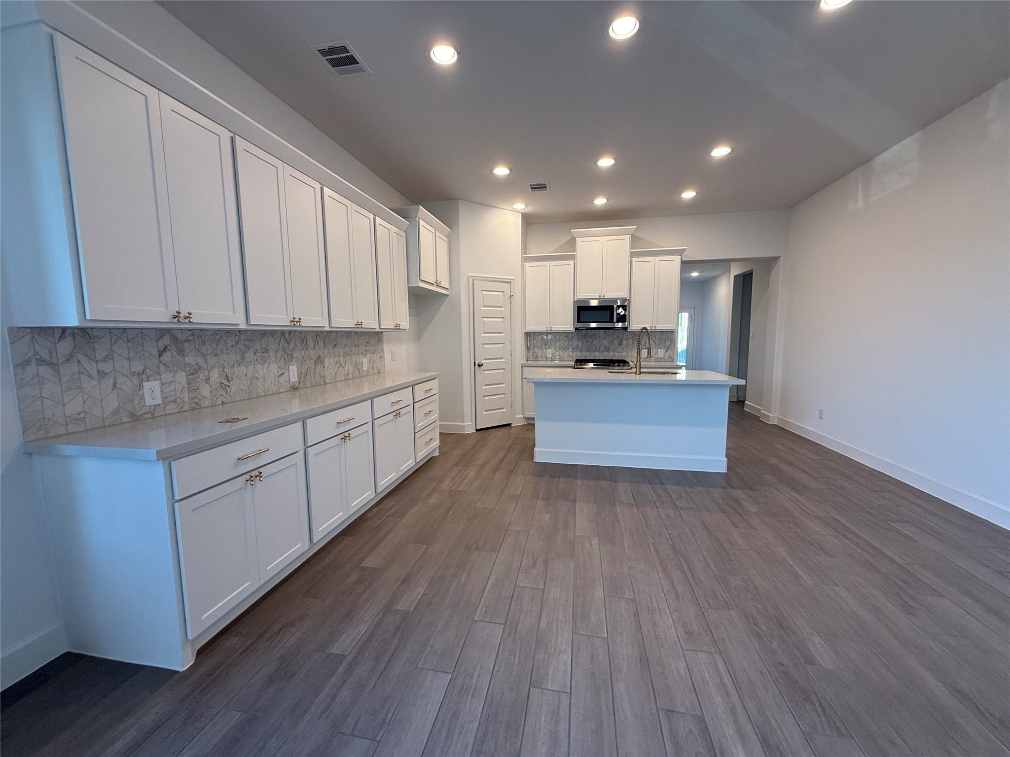 1354 Lakeside Crk Road Magnolia, TX 77354 - Photo 9 of 26 a kitchen with kitchen island granite countertop wooden floors and white cabinets