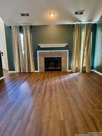 an empty room with wooden floor fireplace and windows