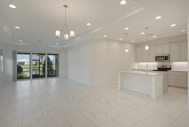 a view of an empty room with kitchen and window