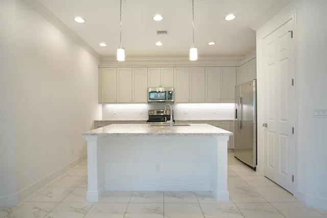a view of a kitchen with kitchen island a sink a counter and a refrigerator