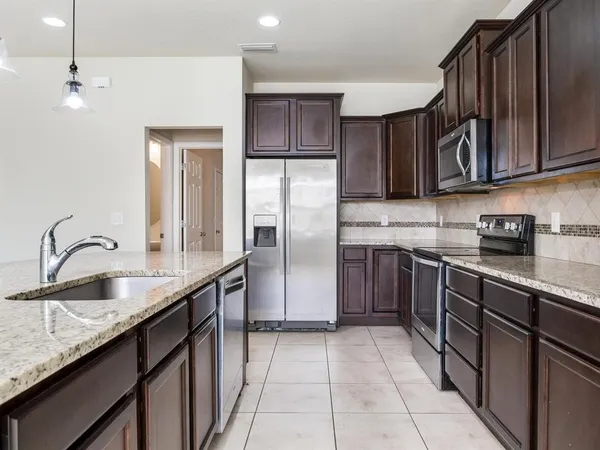 a kitchen with stainless steel appliances granite countertop a sink stove and refrigerator