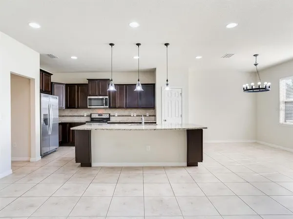 a large kitchen with kitchen island a sink a counter top stainless steel appliances and cabinets