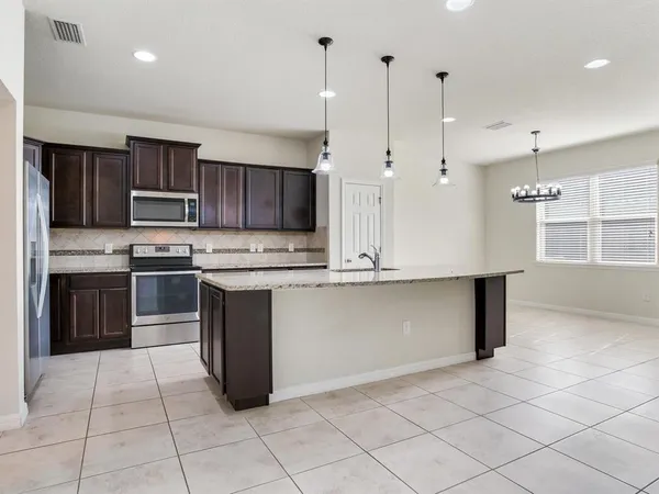a large kitchen with granite countertop a large counter top stainless steel appliances and cabinets