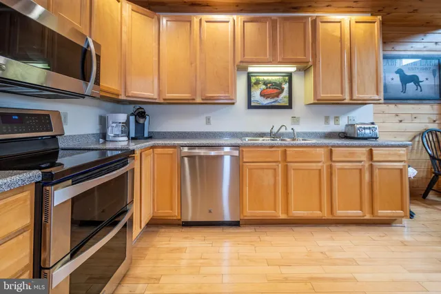 a kitchen with stainless steel appliances granite countertop a stove a sink and a microwave
