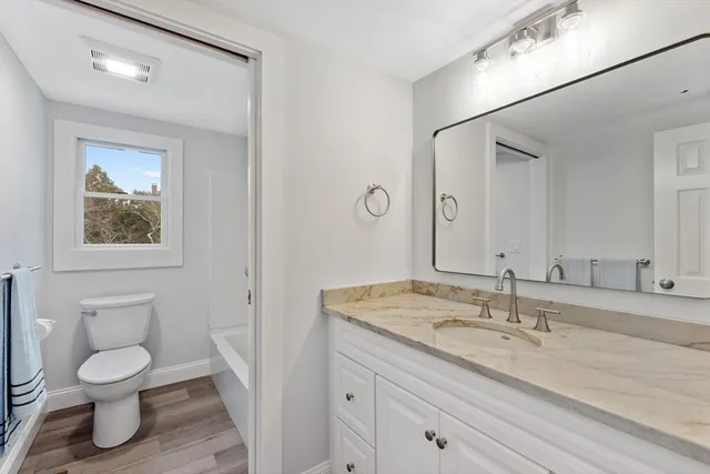 a bathroom with a granite countertop toilet sink and mirror