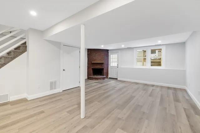 an empty room with wooden floor fireplace and windows