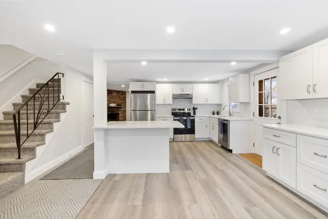 a large white kitchen with lots of counter space wooden floor and appliances